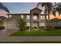 Two-story home showcasing manicured lawn and lush tropical landscaping, complemented by a two car garage at 10068 Chardonnay Dr, Orlando, FL 32832