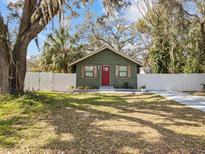 Charming bungalow with updated lawn, a red door, wood shutters, and a white picket fence at 130 Mandrake St, Orlando, FL 32811