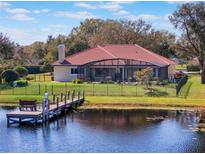 Beautiful backyard view of waterfront home, featuring a dock and a screened-in porch with a red tile roof at 13509 Lake Luntz Dr, Winter Garden, FL 34787