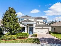 Charming two-story home featuring a brick driveway, blue accents, and manicured landscaping at 15863 Citrus Grove Loop, Winter Garden, FL 34787