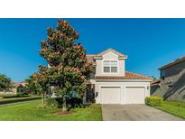 Two-story home features a spacious two car garage and a manicured front lawn with mature tree at 2621 Archfeld Blvd, Kissimmee, FL 34747