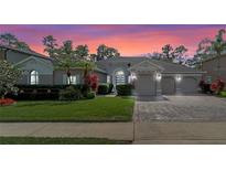 Beautiful home with a well-manicured lawn, palm trees, and a three-car garage at sunset at 3205 Heirloom Rose Pl, Oviedo, FL 32766