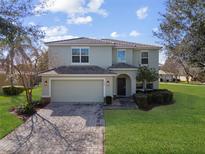 Charming two-story home featuring a paver driveway, tile roof, and lush landscaping at 9026 Paolos Pl, Kissimmee, FL 34747