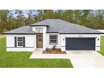 Charming single-story home with modern white exterior, gray roof and a dark gray two car garage at 16074 Sw 49Th Court Rd, Ocala, FL 34473