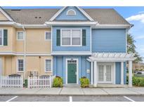 Charming two-story townhome with blue siding, a green door, and a white pergola over the entrance at 4004 San Gallo Dr # 107, Kissimmee, FL 34741