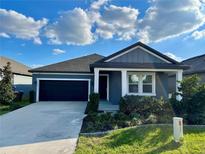 Charming single-story home with a well-maintained lawn, black two-car garage door and manicured landscaping at 5752 Iron Brand Rd, St Cloud, FL 34771