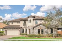 Elegant two-story home featuring a turret, stone accents, tile roof, and well-manicured landscaping at 5774 Fulham Pl, Sanford, FL 32771