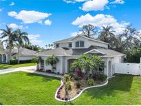 Beautiful two-story home with lush landscaping, palm trees, and manicured lawn on a sunny day with scattered clouds at 795 Sterling Chase Dr, Port Orange, FL 32128