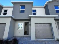 Modern townhome exterior featuring gray stucco, a one-car garage, and an inviting front entrance at 1213 S Station Pl # 404, Orlando, FL 32827