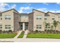 Modern townhome exterior featuring stone accents, green doors, and well-manicured landscaping at 994 Splash Shot Pl, Davenport, FL 33896