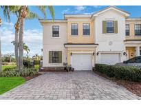 Two-story townhouse featuring a two-car garage, landscaped yard, and a beautiful brick driveway at 3446 Allegra Cir, St Cloud, FL 34772