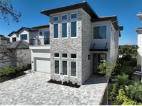 Modern two-story home featuring a stone facade, large windows, and a paved driveway at 1074 E Jack Nicklaus Ct, Kissimmee, FL 34747