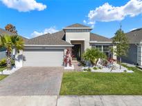 Charming single-story home with a brick driveway, well-manicured lawn, and lovely tropical landscaping at 1204 Pando Loop, Orlando, FL 32824