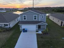 Two-story home with a two-car garage, landscaped front yard, and water view at sunset at 1926 Golden Beak Dr, Eagle Lake, FL 33839