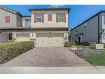 Townhouse with brick paved driveway, two-car garage, well-maintained bushes, and neutral color scheme at 2523 Econ Landing Blvd, Orlando, FL 32825