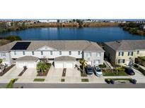 An aerial view of townhomes featuring solar panels and a serene lake backdrop at 360 Arbor Lakes Dr, Davenport, FL 33896