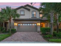 Beautiful home exterior featuring a brick driveway and attached garage, enhanced by mature palm trees and professional landscaping at 8920 Rhodes St, Kissimmee, FL 34747