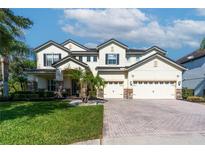 Beautiful two-story home featuring a brick driveway, three-car garage, and meticulously manicured lawn at 1910 Lake Roberts Landing Dr, Winter Garden, FL 34787