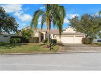 Charming single-story home featuring a lush front yard, a palm tree, and a spacious three-car garage at 305 Grand Reserve Dr, Davenport, FL 33837