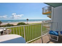 Inviting balcony view showcasing oceanfront scenery with lush green grass leading to the sandy beach at 5201 S Atlantic Ave # 301A, New Smyrna Beach, FL 32169