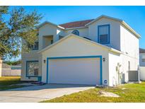 Two-story home featuring blue trim, a driveway, a 2-car garage, and grass lawn at 608 Bluebill Ct, Kissimmee, FL 34759