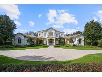 Beautifully landscaped front yard view of a stately home with a circular driveway and manicured garden beds at 6126 Kirkstone Ln, Windermere, FL 34786