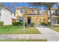 Inviting two-story home with a well-manicured lawn, lush landscaping, and an attached single-car garage at 8961 Cuban Palm Rd, Kissimmee, FL 34747