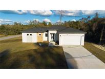 New construction home featuring a modern design, two-car garage and a well-manicured lawn at 15215 Sw 43Rd Ct, Ocala, FL 34473