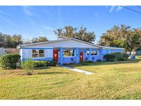 Charming single-story home with a well-maintained lawn, vibrant blue paint, and inviting red doors at 200 Dr Martin Luther King Jr Se St, Fort Meade, FL 33841