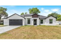 A modern home exterior features a white stucco facade, black trim, gray roof, and a dark gray garage door at 2150 Corbett Rd, Orlando, FL 32826