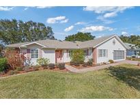 Charming home featuring a landscaped front yard, brick walkway, pink shutters and door at 26913 Forest Hills St, Leesburg, FL 34748