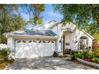 Charming one-story home boasts a white facade, arched entry, two-car garage, and well-manicured landscaping at 3825 Pickwick Dr, Orlando, FL 32817