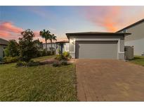 Charming single-story home with a two-car garage and manicured lawn at sunset at 3838 Marbella Way, Davenport, FL 33897