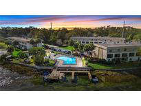 Stunning aerial view of condo complex with pool, boat docks, and sunset at 402 E Orlando Ave # 18C, Ocoee, FL 34761