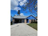 Charming single-story home featuring blue siding, brick accents, and a spacious driveway on a sunny day at 703 Pine Shores Cir, New Smyrna Beach, FL 32168