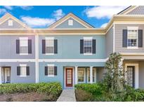 Charming two-story townhome featuring a red door and neatly landscaped front yard at 10226 Vickers Ridge Dr, Orlando, FL 32829