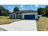 Charming single-story home showcasing a well-manicured lawn and a blue two-car garage at 11 Spruce Ln, Ocala, FL 34472