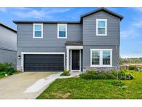 Two-story gray home featuring an attached garage, manicured lawn and stone accents at 2222 Derwent Dr, Davenport, FL 33896