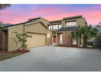 Inviting two-story home with tan siding, brick accents, attached garage, and a well-manicured front yard at 229 Springside Rd, Longwood, FL 32779