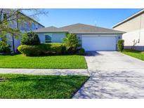 Well-maintained front yard with green grass and tasteful landscaping leading to a two-car garage at 2305 Biscotto Cir, Davenport, FL 33897