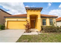 Charming yellow home featuring a tile roof, well-manicured lawn, and a welcoming front porch at 2610 Rosemont Cir, Davenport, FL 33837