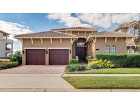 Elegant home featuring a tile roof, symmetrical landscaping, and a two-car garage on a sunny day at 314 Muirfield Loop, Reunion, FL 34747