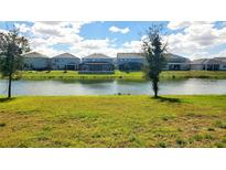 A serene backyard view of a waterfront property, showcasing the tranquil pond and lush green lawn at 5030 Tibet Ct, St Cloud, FL 34772