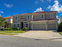 Two-story home featuring a red tile roof, a three-car garage, and landscaped greenery at 6004 Oak Green Loop, Davenport, FL 33837