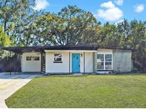 Charming one story home featuring a well-maintained lawn, blue front door, and covered parking at 117 Shannon Dr, Sanford, FL 32773