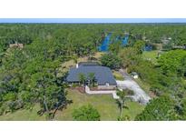 Beautiful aerial view of a brick home featuring a lush, treed landscape and a tranquil lake backdrop at 1303 Sultan Cir, Chuluota, FL 32766