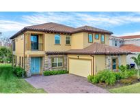 Stunning two-story home with a tile roof, stone accents, a small balcony, and manicured landscaping at 13169 Bromborough Dr, Orlando, FL 32832