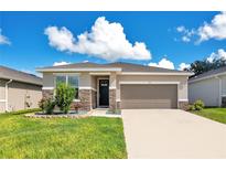 Charming single Gathering home featuring stone accents, neutral paint, manicured lawn and a two car garage at 132 Lake Smart Cir, Winter Haven, FL 33881