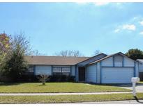 Charming single-story home with attached garage, blue trim, and a well-maintained front lawn at 1542 Colony Ave, Kissimmee, FL 34744