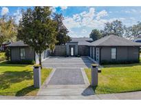 Contemporary home featuring a sleek gray exterior, stone accents, and a beautifully landscaped front yard at 2010 Hoffner Ave, Belle Isle, FL 32809